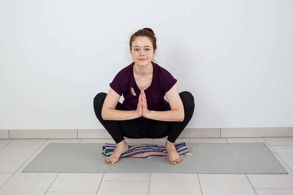 blanket under heels for support in yoga squat
