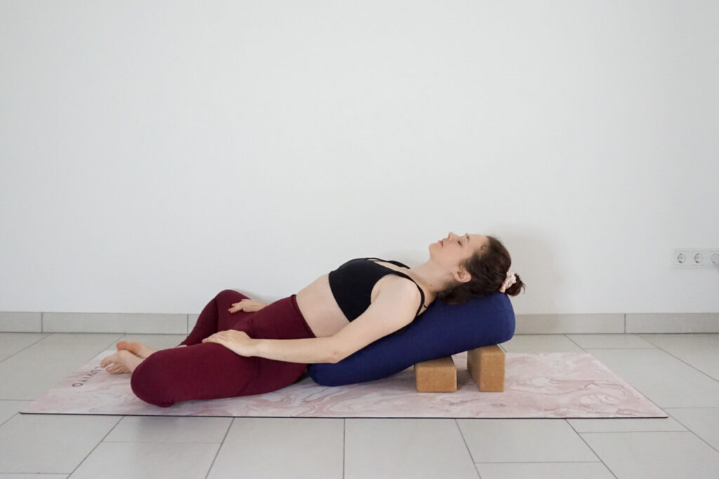 restorative reclined butterfly pose with yoga bolster and blocks