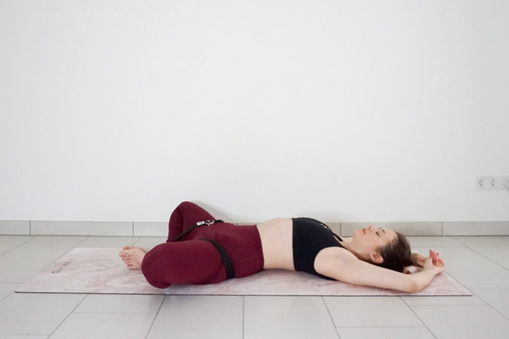 supta baddha konasana with a yoga stap